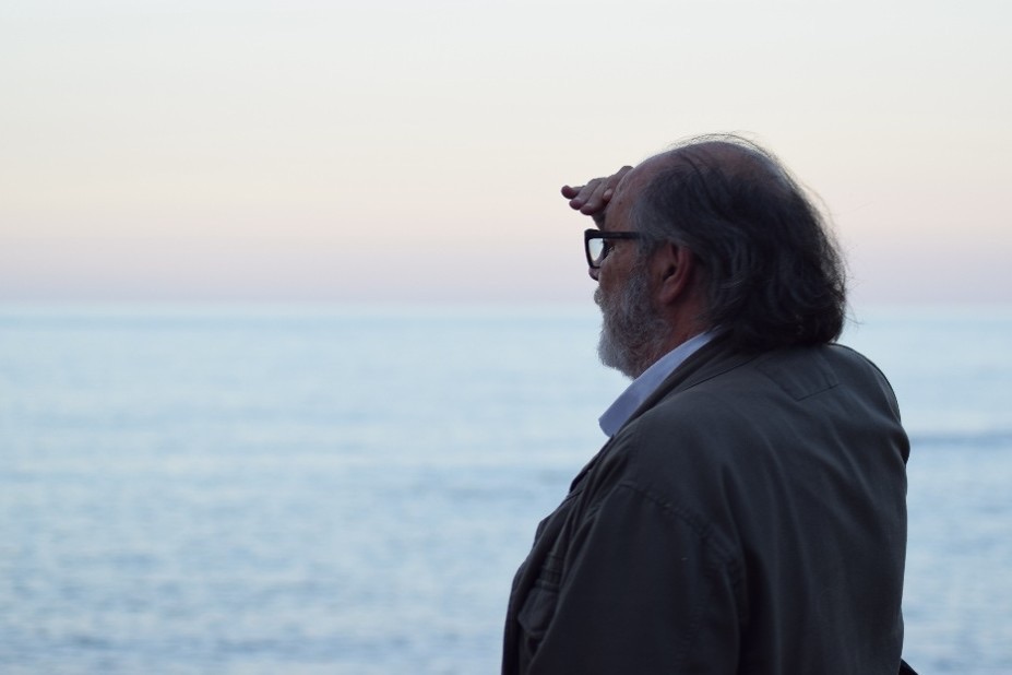 El Caminante, de perfil, se protege los ojos con la mano mientras mira el mar al atardecer
